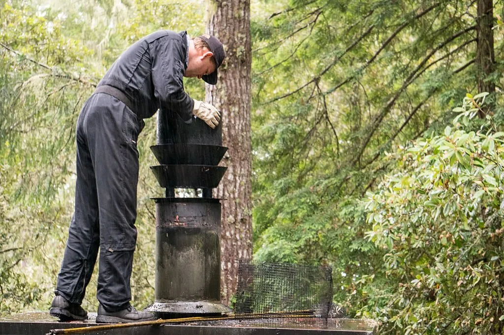 Chimney sweep cleaning a cap in the rain