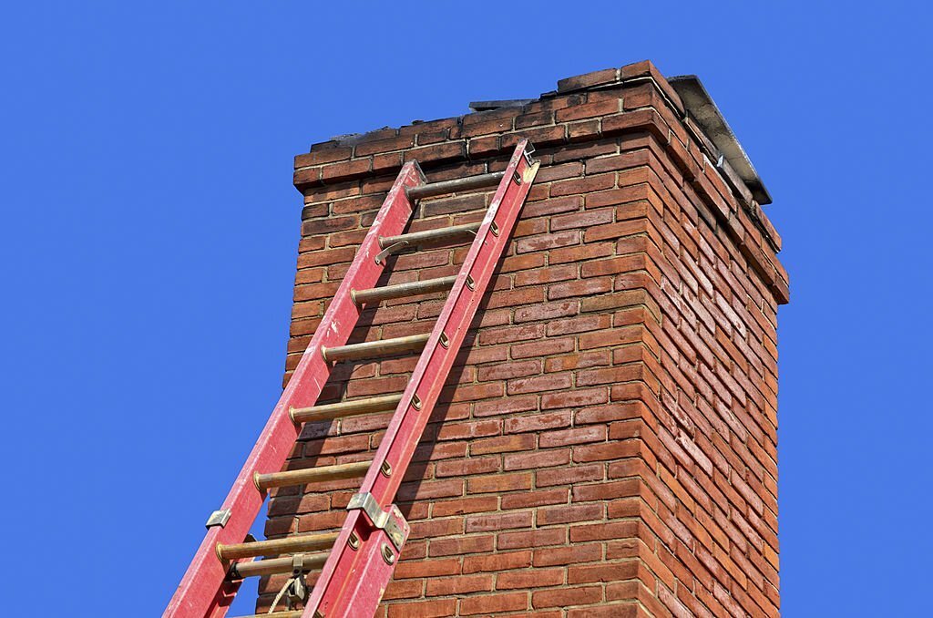 Red ladder against old chimney to make needed repairs