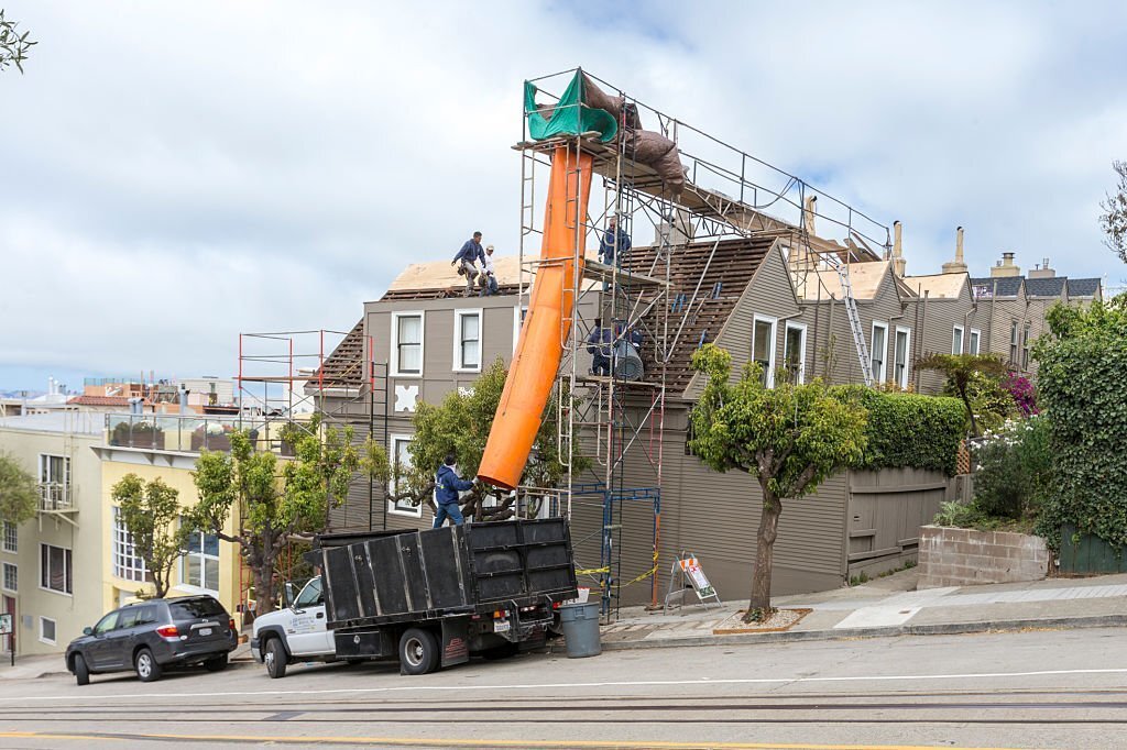 San Francisco, CA, USA - August 25, 2016: House remodeling at downtown of San Francisco. Cable car rail on the bottom. Construction worker are working around the roof of the residential building.