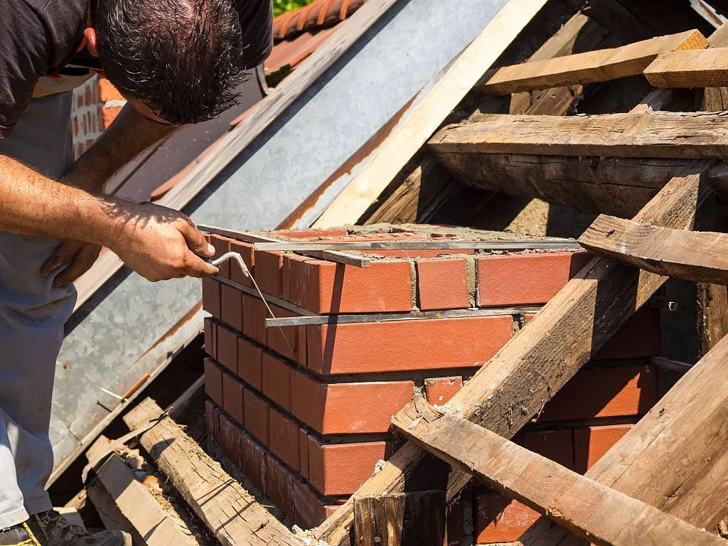 Mason rebuilding a brick chimney